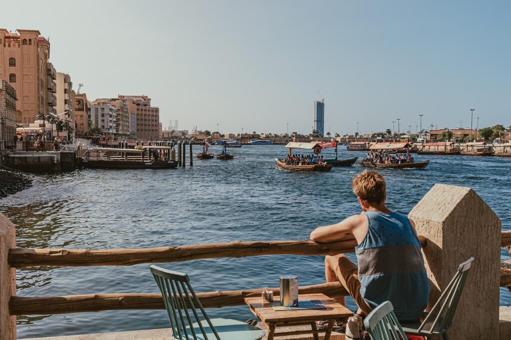 a man watching over a boat passing by at dubai creek
