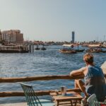 a man watching over a boat passing by at dubai creek